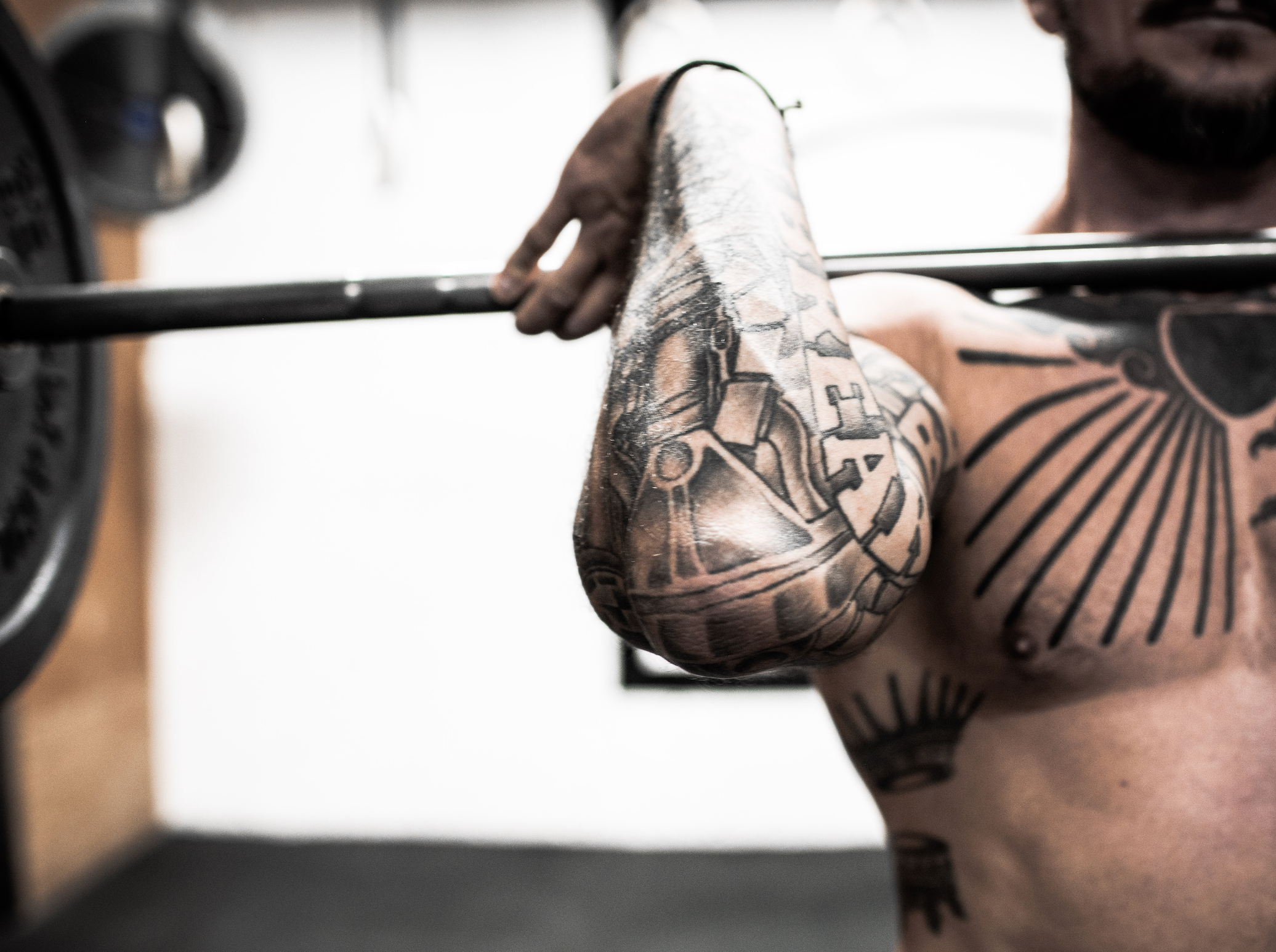 An athlete or CrossFitter lifting weights with the bar curled up on his chest during a workout.