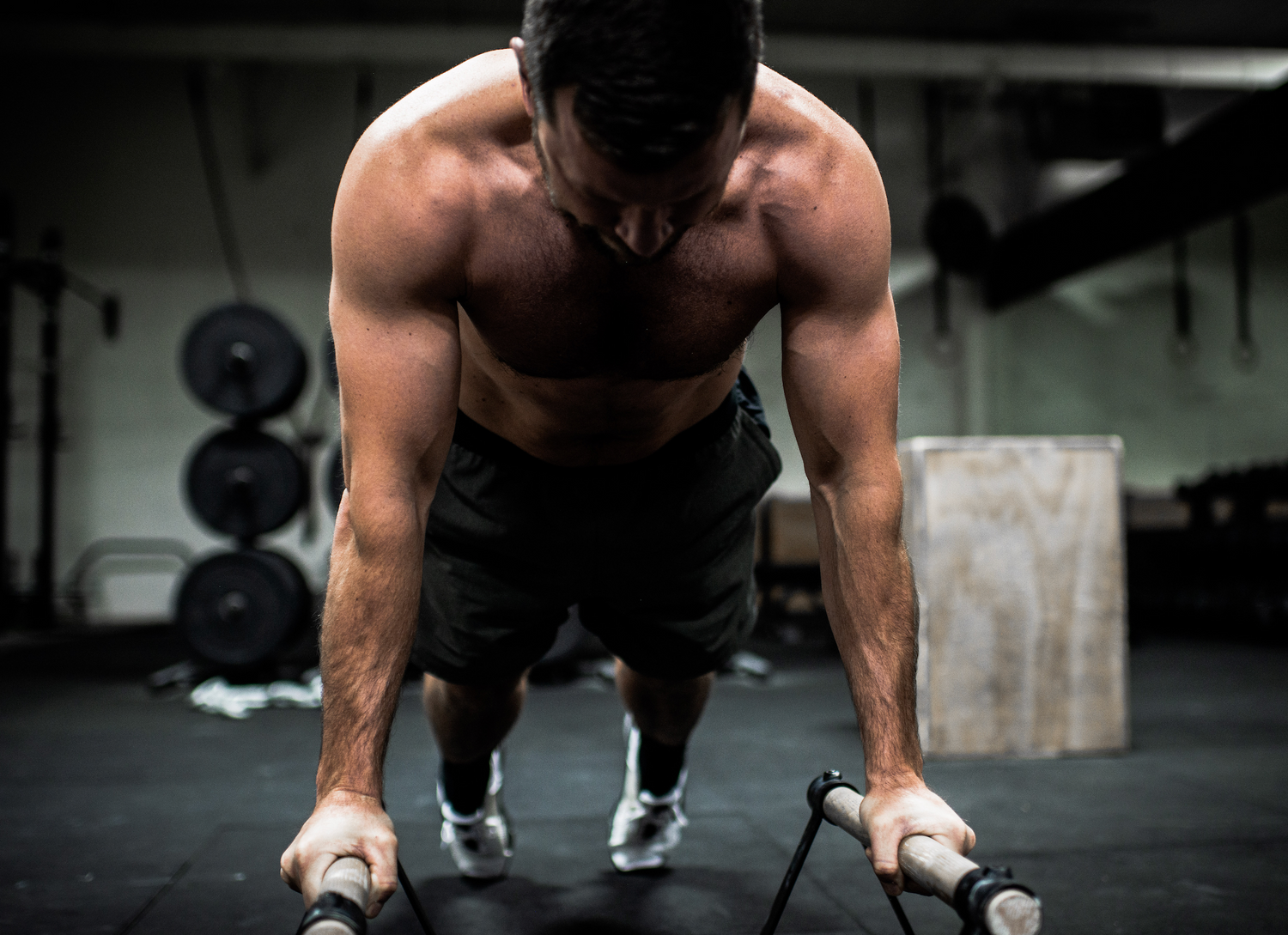 Athlete or crossfitter doing push-ups on a bar with wrapped hands and chalked up for a workout