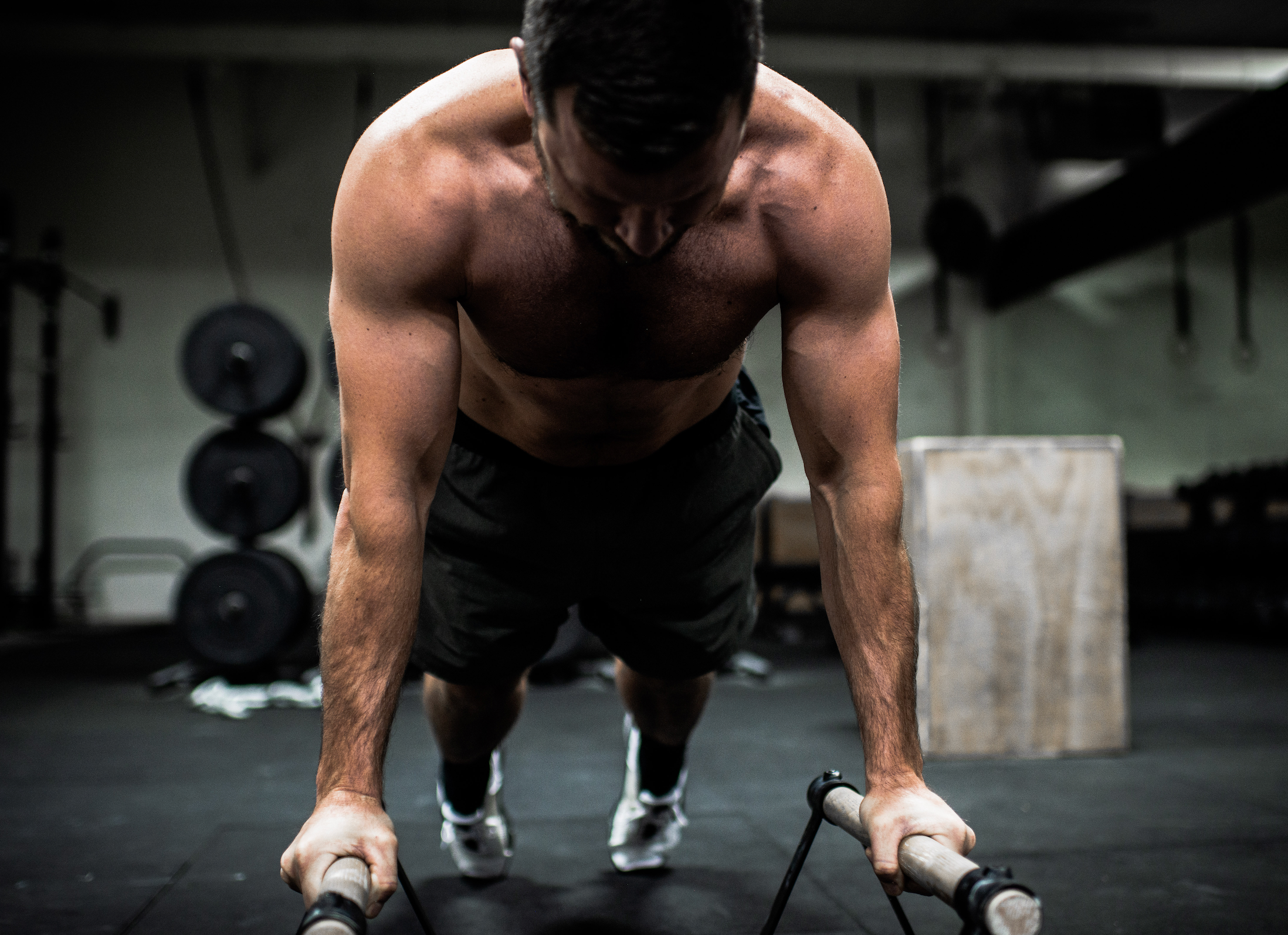 Athlete or crossfitter doing push-ups on a bar with wrapped hands and chalked up for a workout