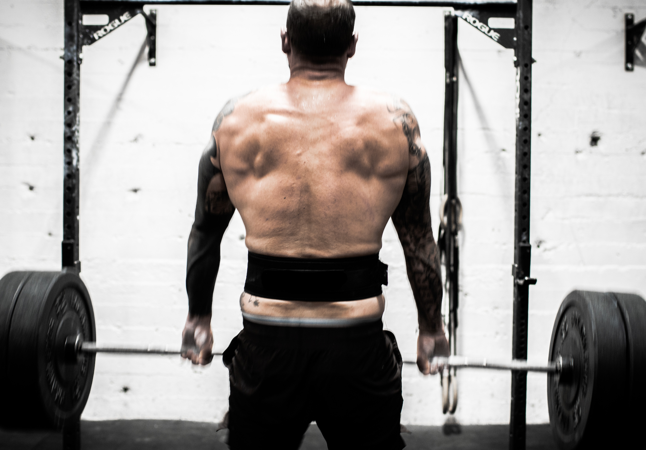 Athlete or crossfitter lifting weights during a workout session, with lots of pressure on his hands.